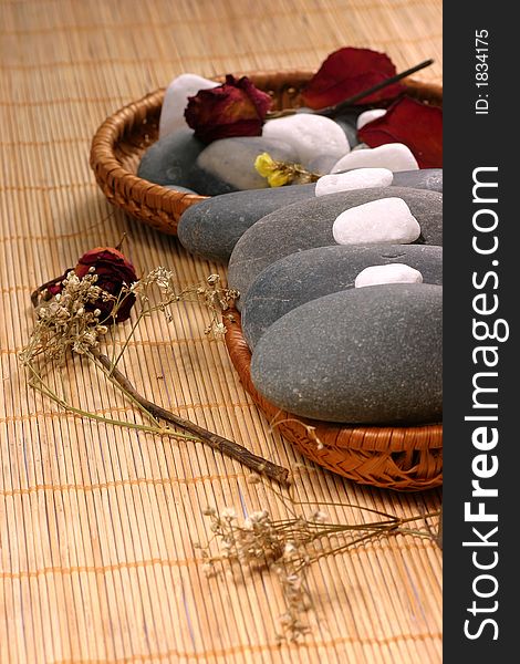 Natural pebbles and dried flowers on the rattan background. Suitable for spa and relaxation setting. Natural pebbles and dried flowers on the rattan background. Suitable for spa and relaxation setting.