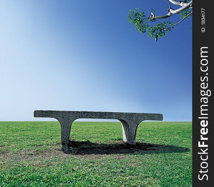 Single cement bench in a park on a clear sunny day. Single cement bench in a park on a clear sunny day