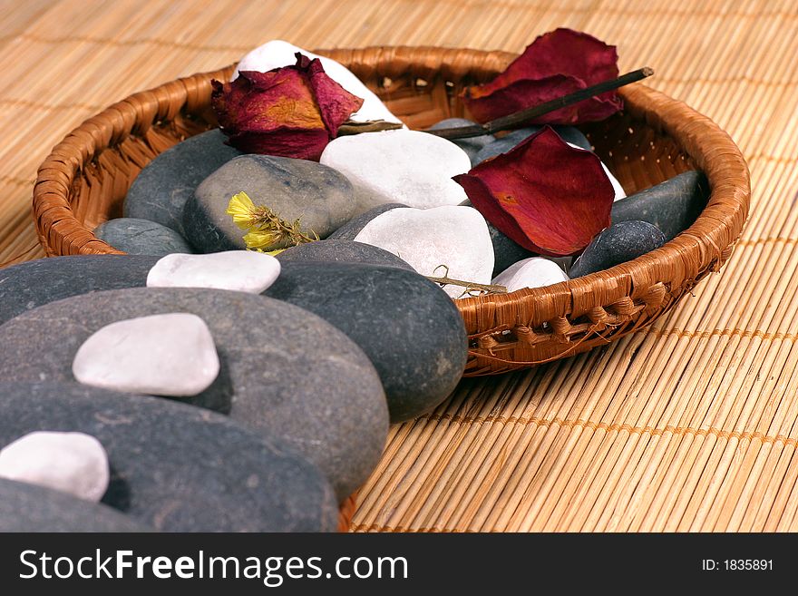 Natural pebbles and dried flowers on the rattan background. Suitable for spa and relaxation setting. Natural pebbles and dried flowers on the rattan background. Suitable for spa and relaxation setting.