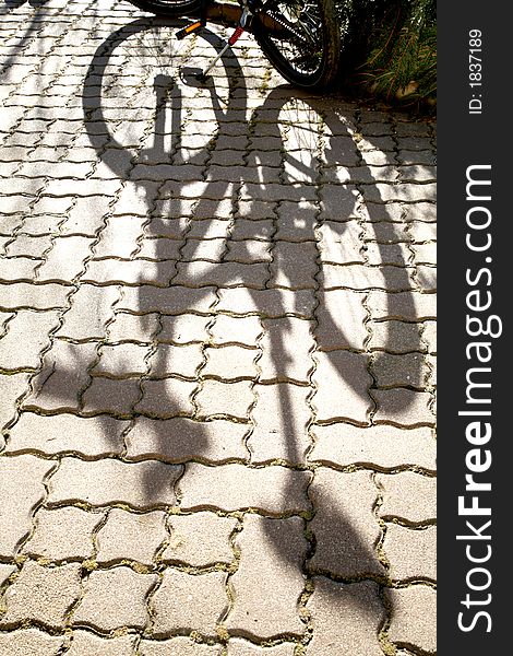 Thr shadow of the bicycle, falling over a regular pattern of cobble. Thr shadow of the bicycle, falling over a regular pattern of cobble