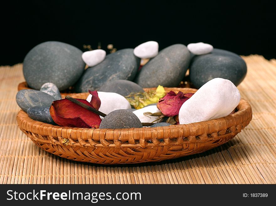 Natural pebbles and dried flowers on the rattan background. Suitable for spa and relaxation setting. Natural pebbles and dried flowers on the rattan background. Suitable for spa and relaxation setting.