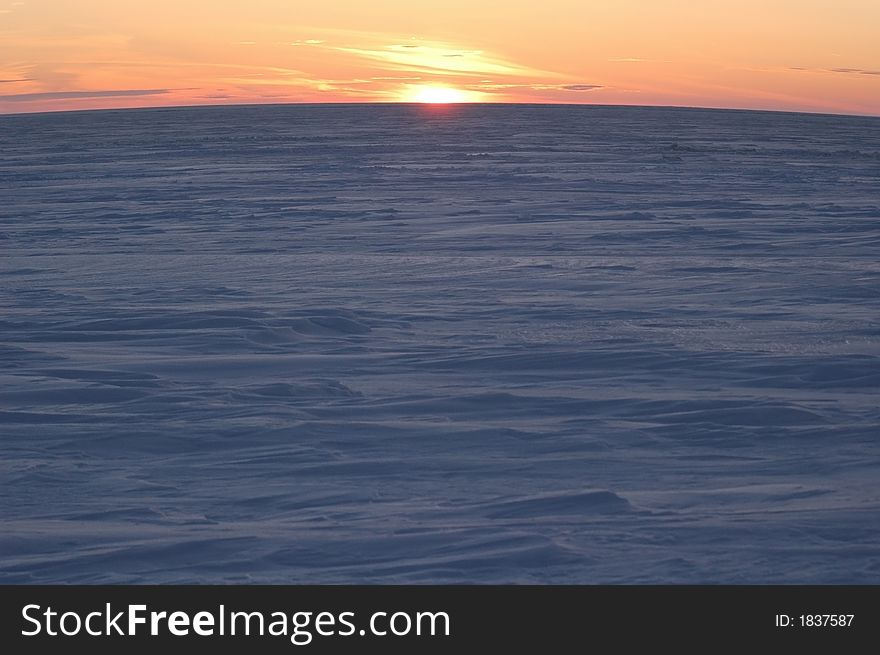 A sunrise is in the north above ice