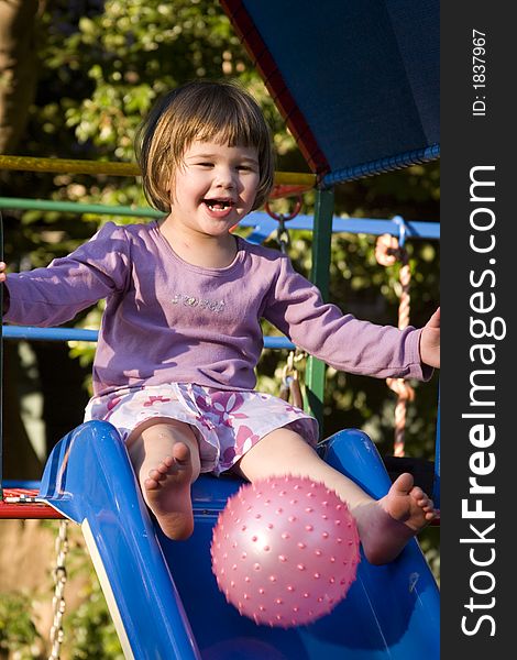 Cute little brunette girl playing with  ball on the slie. Cute little brunette girl playing with  ball on the slie