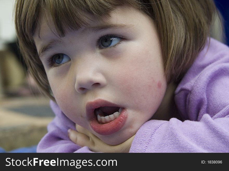 Cute little brunette girl resting on her hands with teeth showing. Cute little brunette girl resting on her hands with teeth showing