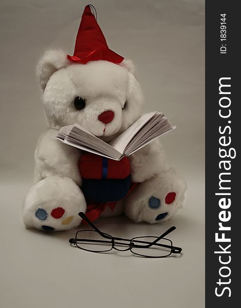 Sitting and reading teddy bear with glasses near and the book under its face