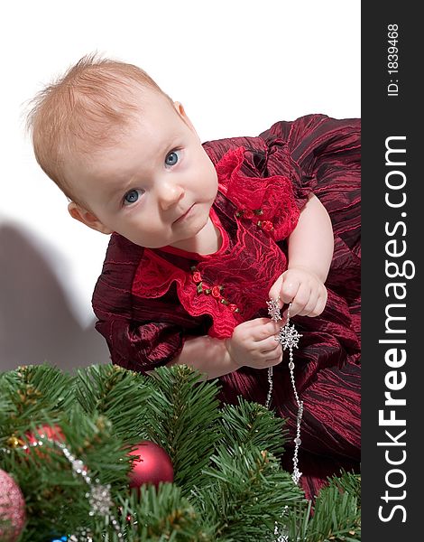 Little baby girl in formal red dress standing next to the Christmas tree. Copy space is on the right top. Little baby girl in formal red dress standing next to the Christmas tree. Copy space is on the right top.