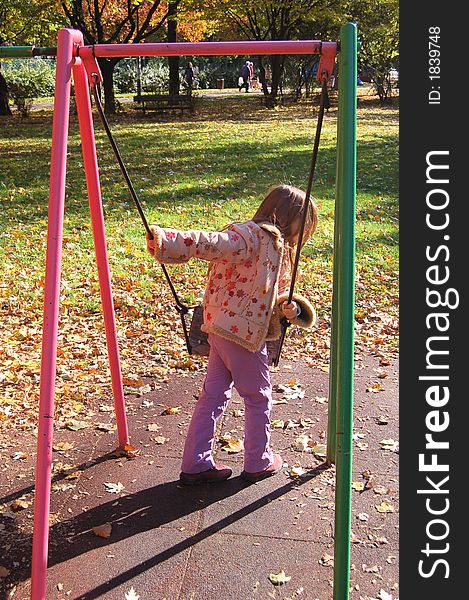 Girl playing on a swing in autumn park. Girl playing on a swing in autumn park.