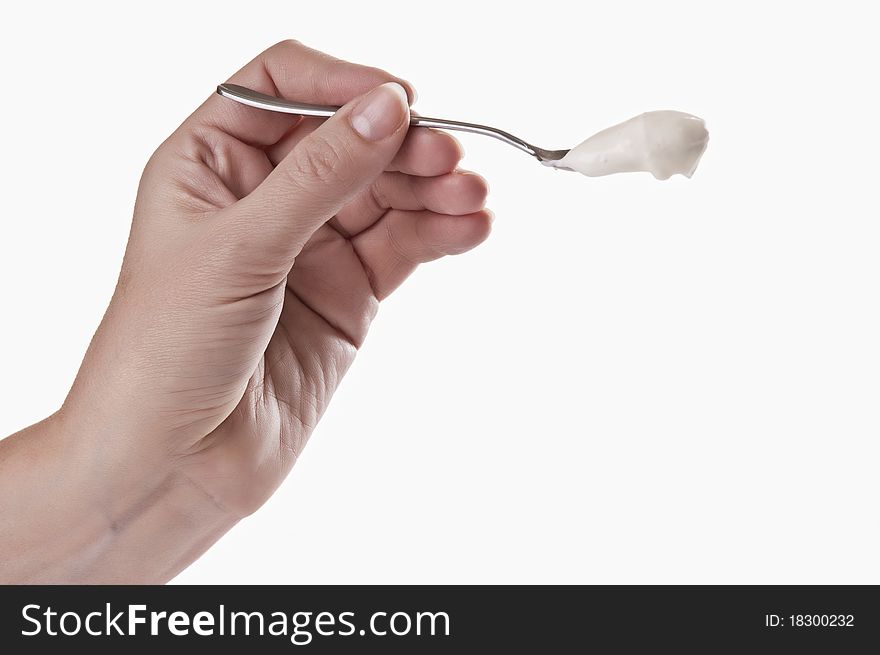 Tea spoon with yoghurt in a hand on a light background