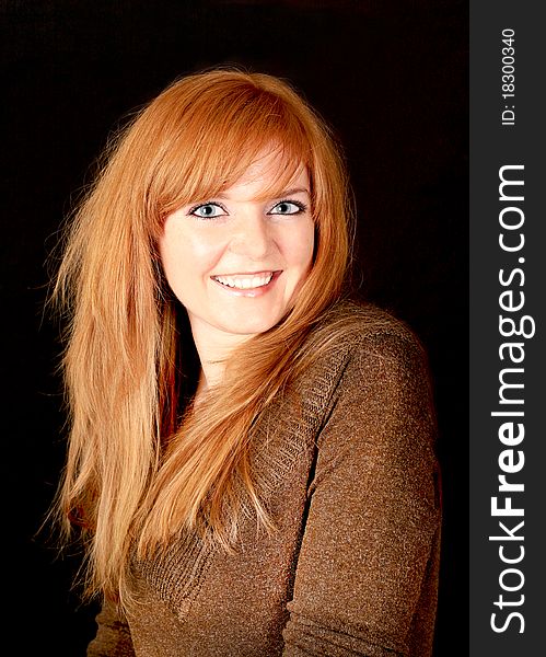 Young red-haired girl smiling on a dark background