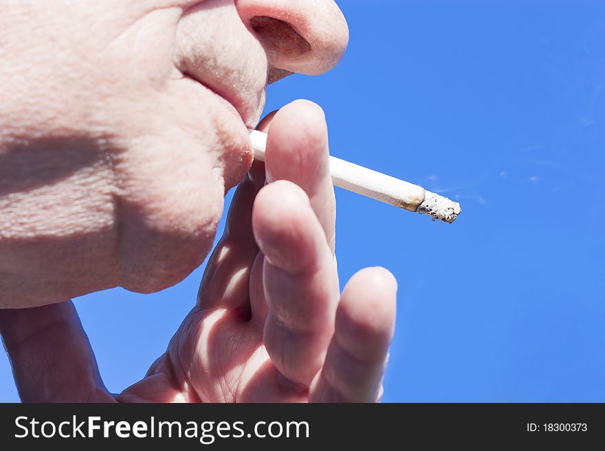 Handheld cigarette on blue background. Handheld cigarette on blue background