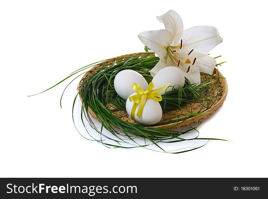 Easter eggs in basket with white lily on white background