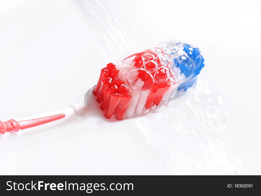 Water pouring on red, white and blue wet toothbrush