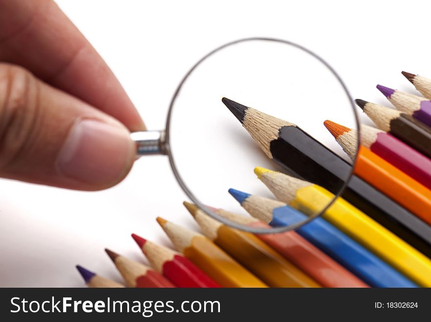 Magnify glass and color pencils in white background