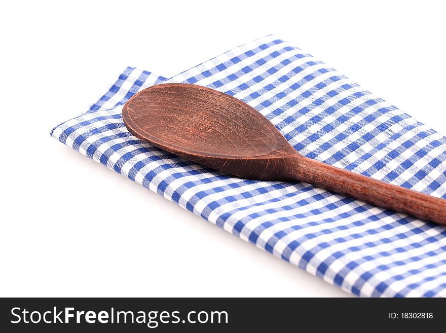 Wooden spoon on checkered dishtowel isolated on white background. Wooden spoon on checkered dishtowel isolated on white background