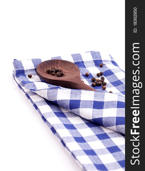 Wooden spoon with peppercorn on dishtowel isolated. Wooden spoon with peppercorn on dishtowel isolated