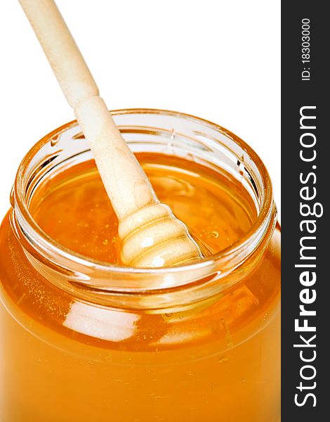 Jar of honey with wooden dipper, isolated on white