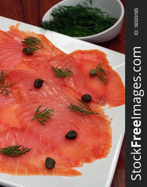 A plate of fresh smoked salmon garnished with dill and capers. A plate of fresh smoked salmon garnished with dill and capers.