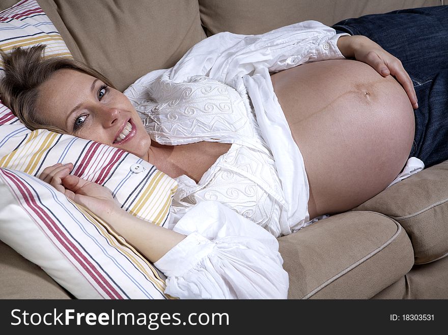 Happy beautiful pregnant woman relaxing on sofa