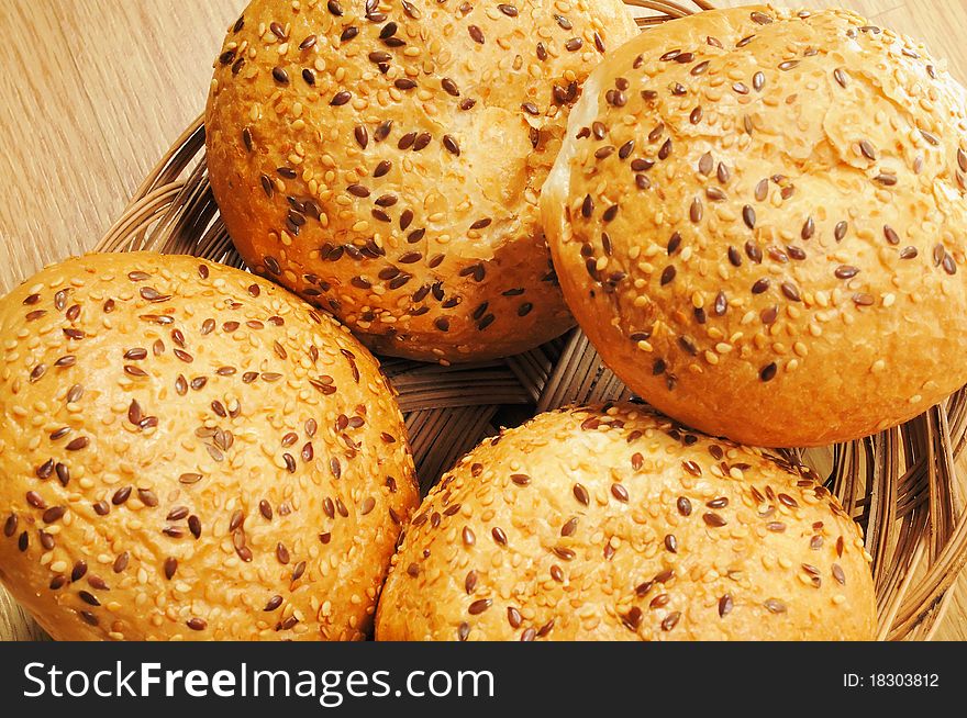 Bun, topped with sesame seeds in a basket on wooden table