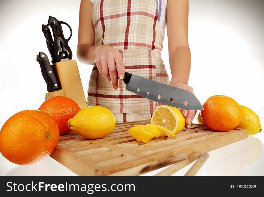 Girl cutting lemons with the knife, on a wooden plate. Girl cutting lemons with the knife, on a wooden plate