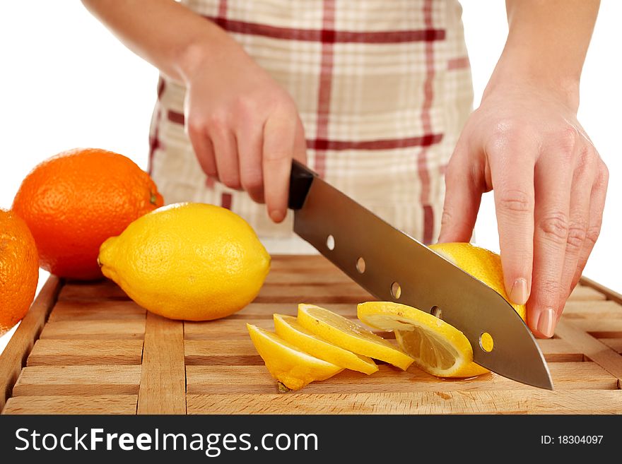 Girl cutting lemons with the knife, on a wooden plate. Girl cutting lemons with the knife, on a wooden plate