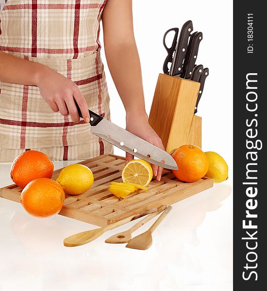 Girl cutting lemons with the knife, on a wooden plate