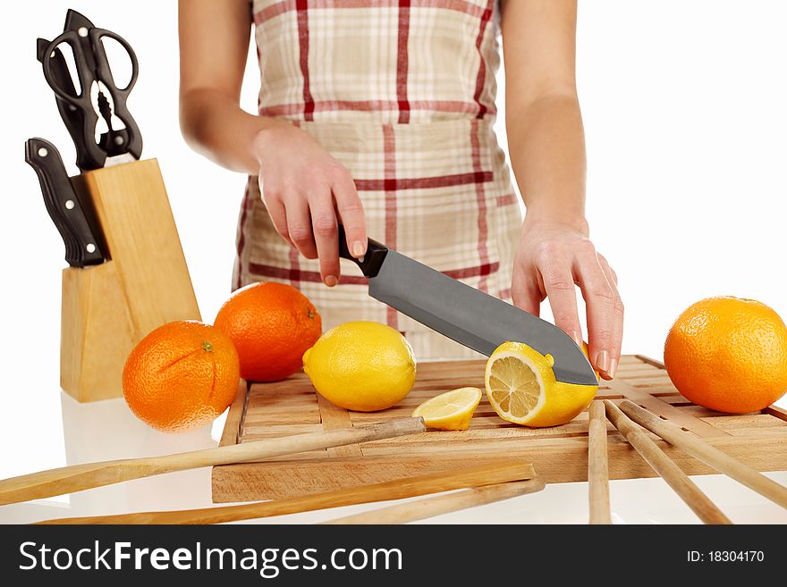 Girl cutting lemons with the knife, on a wooden plate. Girl cutting lemons with the knife, on a wooden plate