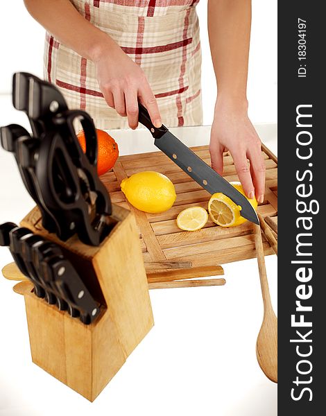 Girl cutting lemons with the knife, on a wooden plate. Girl cutting lemons with the knife, on a wooden plate