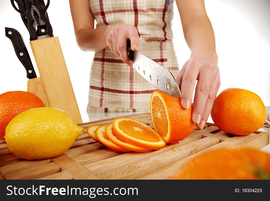 Girl cutting orange with the knife, on a wooden plate. Girl cutting orange with the knife, on a wooden plate