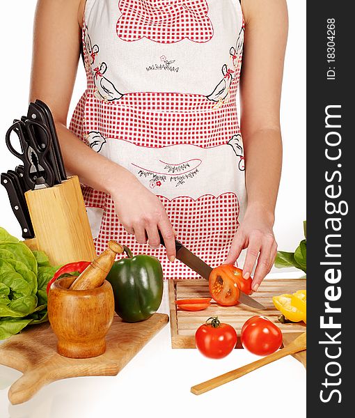 Girl cutting tomato with the knife, on a wooden plate