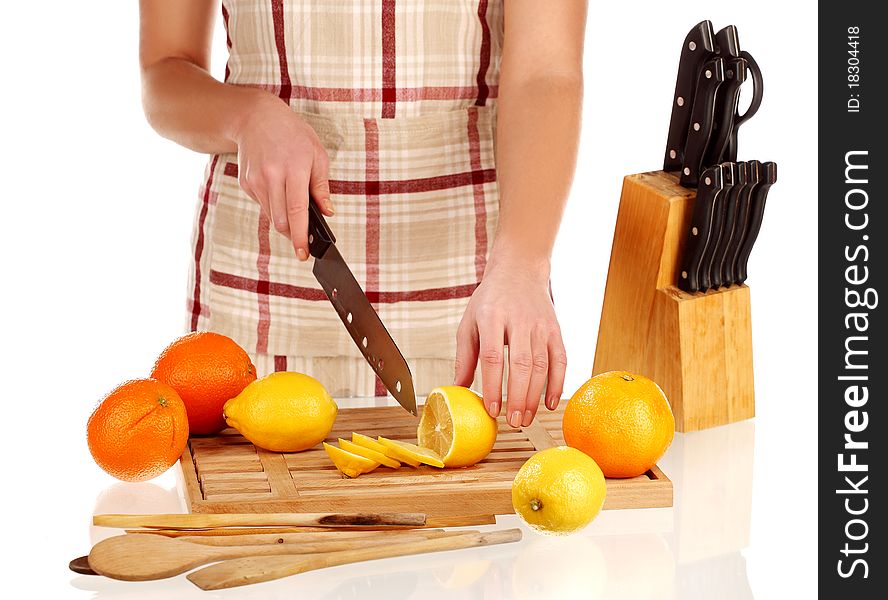 Girl cutting lemons with the knife, on a wooden plate. Girl cutting lemons with the knife, on a wooden plate