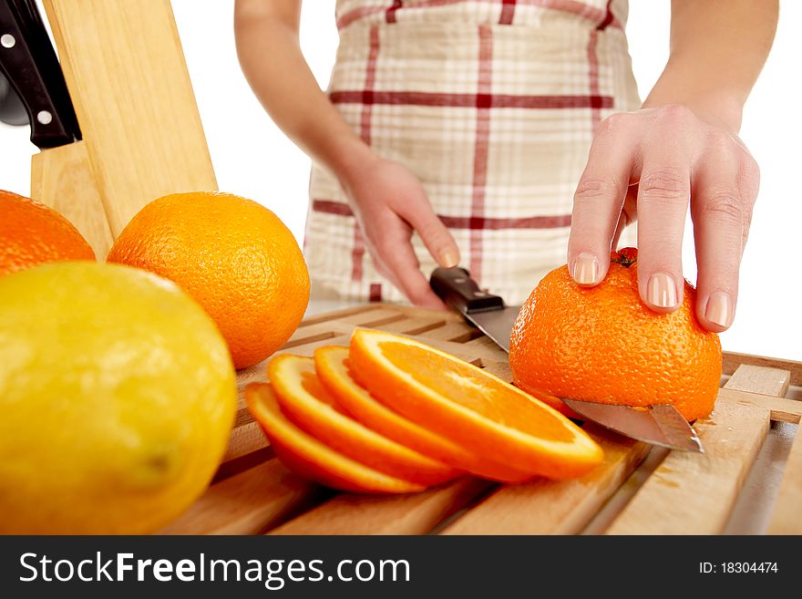 Girl cutting orange with the knife, on a wooden plate. Girl cutting orange with the knife, on a wooden plate