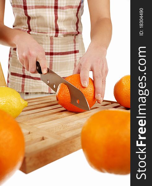 Girl cutting orange with the knife, on a wooden plate. Girl cutting orange with the knife, on a wooden plate