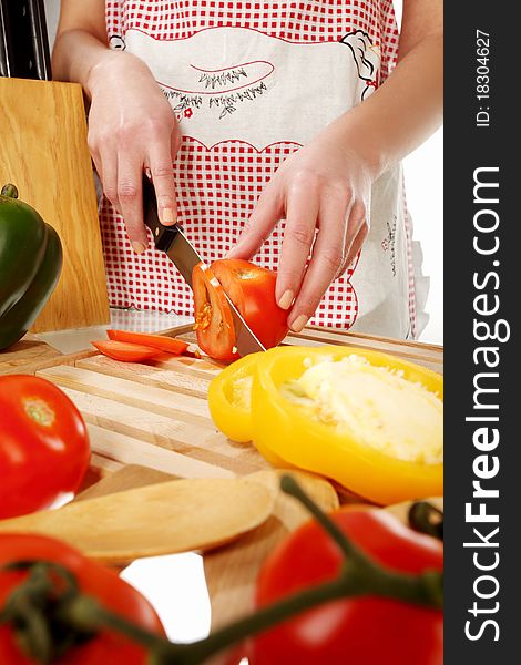 Girl cutting tomato with the knife, on a wooden plate. Girl cutting tomato with the knife, on a wooden plate