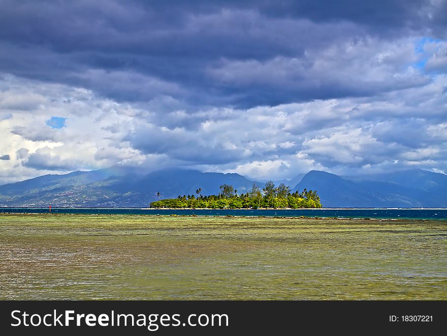 Motu is a small island on the reef, from Moorea island with Tahiti behind the clouds. Motu is a small island on the reef, from Moorea island with Tahiti behind the clouds.