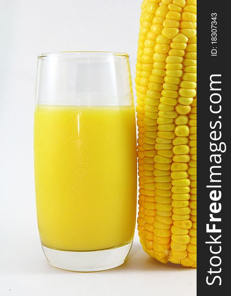 A glass of corn juice on a white background ,with corn by side