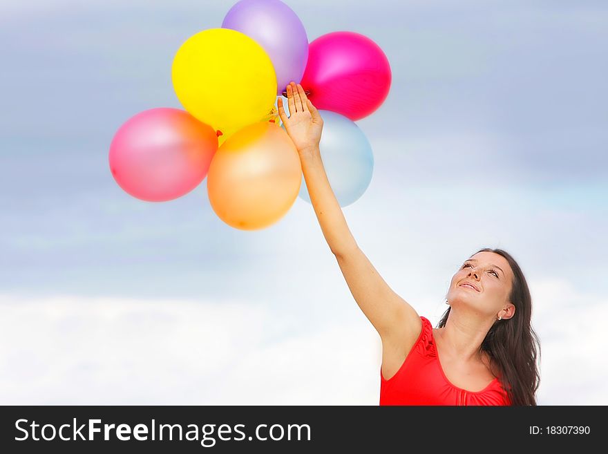 Young attractive woman with colorful balloons on sky background