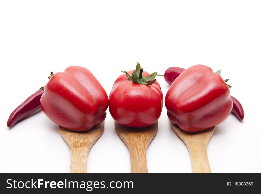 Red paprikas and tomato onto cook spoons