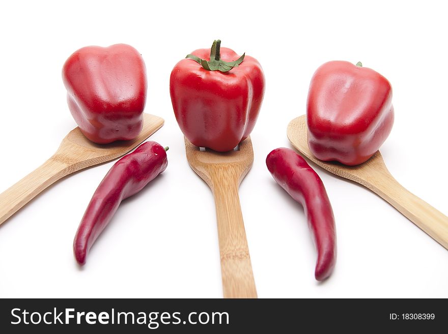 Red paprikas and tomato onto cook spoons