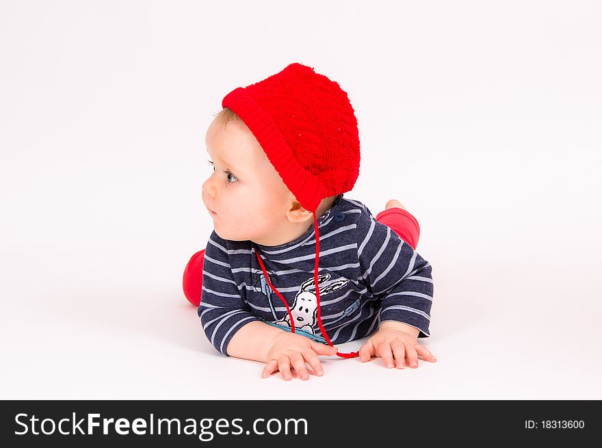 Little child baby in a red hat lying on the floor