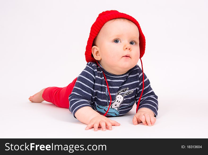 Little child baby in a red hat lying on the floor