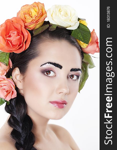 Portrait of young beautiful woman with roses in hair, on white background