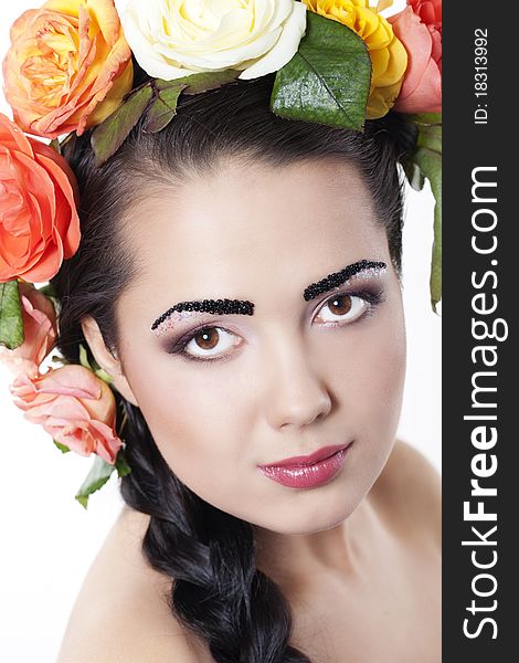 Portrait of young beautiful woman with roses in hair, on white background