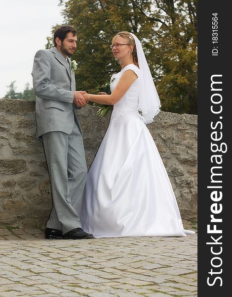 Groom and bride staying on a stone bridge