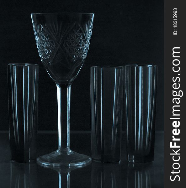 Empty glass wine-glasses in dark blue tones on a black background. Empty glass wine-glasses in dark blue tones on a black background