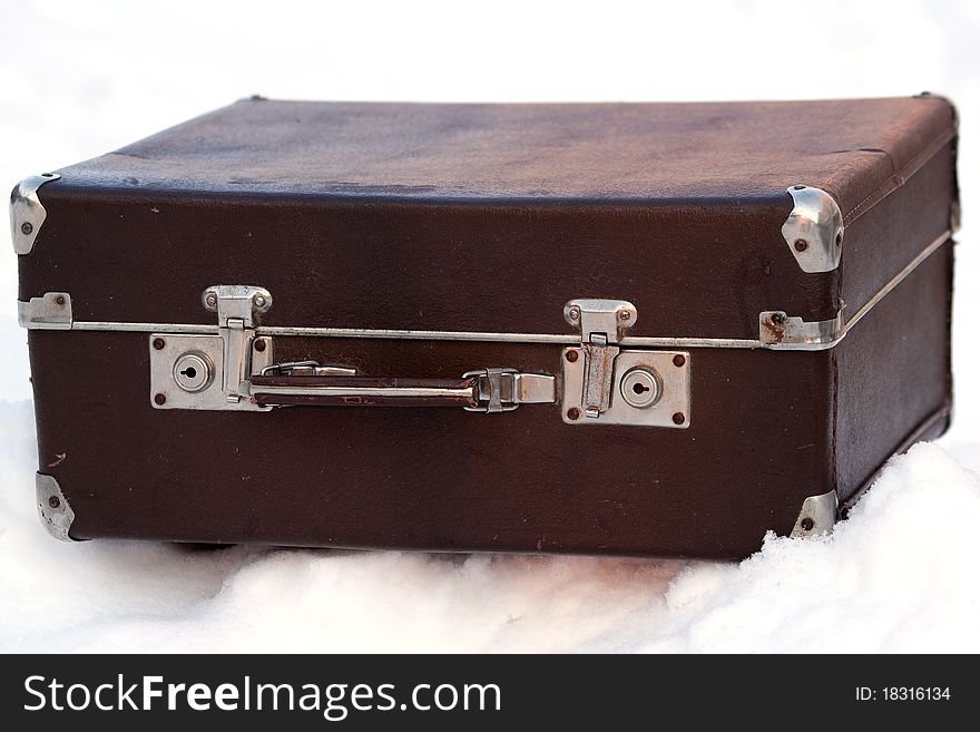 Ancient suitcase fitted by a skin on snow in the winter. Ancient suitcase fitted by a skin on snow in the winter
