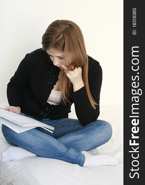 Teenage girl reading and learning in her bed isolated on white background. Teenage girl reading and learning in her bed isolated on white background