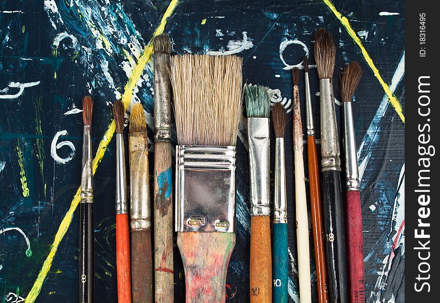 Paintbrushes lying on a blue-yellow paintig, art and craft equipment