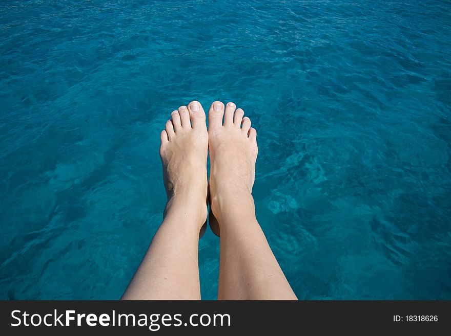 Sunbathing legs over turquoise blue water. Sunbathing legs over turquoise blue water.