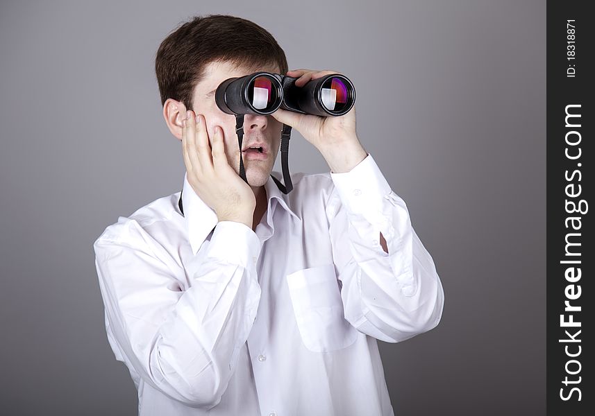 Young surprised businessmen in t-shirt with black binocular. Studio shot. Young surprised businessmen in t-shirt with black binocular. Studio shot.